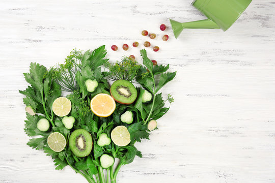 Cute bouquet of parsley and dill decorated with kiwi, lemons and cucumbers on light wooden background