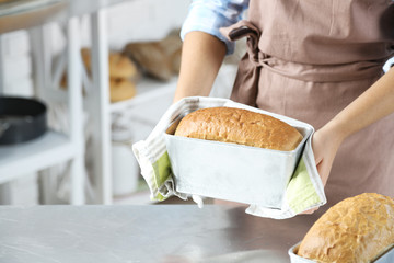 Baker checking freshly baked bread in kitchen of bakery