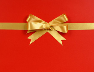 Gold gift bow ribbon straight horizontal banner isolated on red wrapping paper background for...