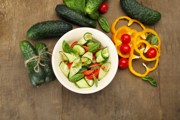 Vegetable salad with cucumbers and pepper on wooden background