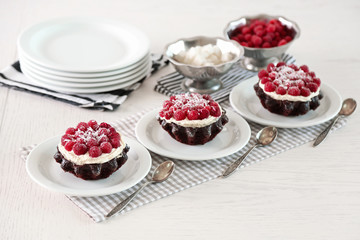 Sweet cakes with raspberries on light wooden background