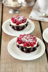 Sweet cakes with raspberries on light wooden background