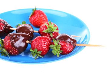 Delicious strawberries in chocolate on a blue plate, isolated on white