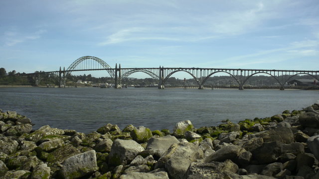 The Yaquina Bay Bridge in Newport, OR. Shot from the south jetty looking inland, two birds fly into shot and towards bridge.