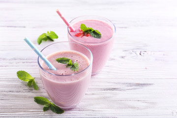 Fresh strawberry and milk yogurts with mint on light wooden background