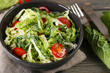 Savoy cabbage and tomato salad served in bowl on wooden table