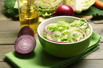 Savoy cabbage and onion salad served in bowl on wooden table