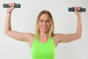 Smiling blond woman doing exercises with dumbbells