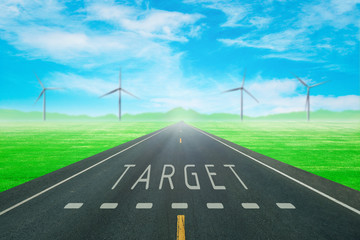 road through the green field with sign target on asphalt