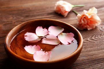 Obraz na płótnie Canvas Pink rose petals in a bowl of water on wooden background