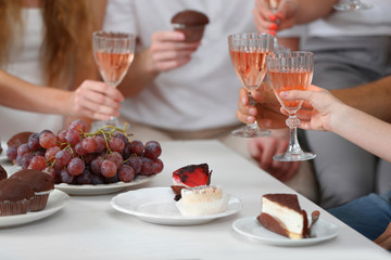 Friends hands with glasses of wine and desserts, close up