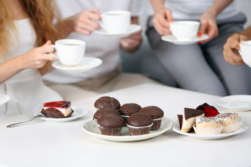 Friends hands with desserts and cups of tea, close up