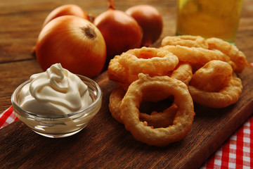 Chips rings with sauce and onion on cutting board closeup