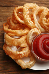 Chips rings with red sauce on plate on wooden background