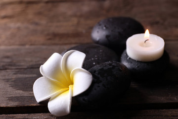 Fototapeta na wymiar Relaxing concept - fragipani flower, pebbles and candles on wooden background