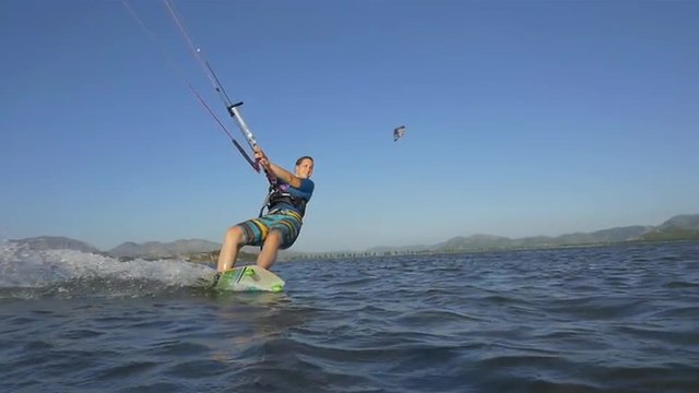  SLOW MOTION: Kiteboarding girl splashes water into kamera while riding
