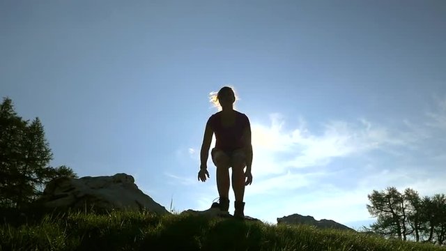 SLOW MOTION: Female hiker jumping up on top of the mountain