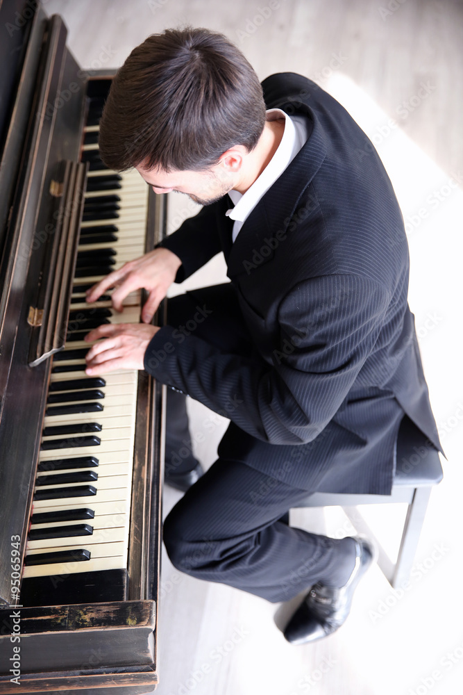 Poster Handsome man in black suit plays piano in the class