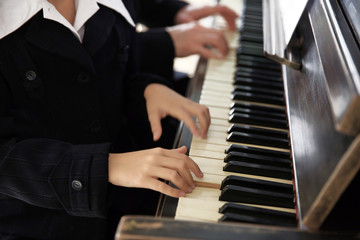 Fototapeta na wymiar Musician teacher trains to play piano little girl, close up