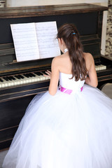 Attractive little princess girl plays piano
