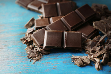 Black chocolate pieces on color wooden background