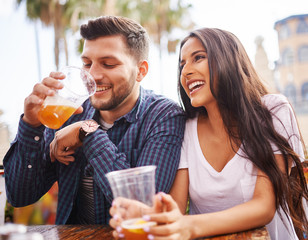 hispanic couple drinking beer on date together at outdoor patio