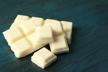 White chocolate pieces on color wooden background