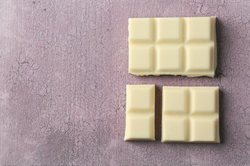 White chocolate pieces on color wooden background