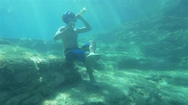 UNDERWATER: Young man drinking beer under water