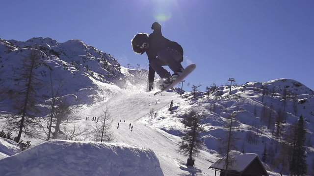 SLOW MOTION: Snowboarder jumping over the sun
