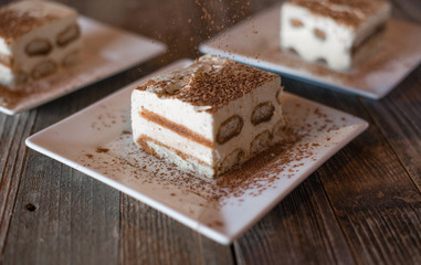 Tiramisu being topped with cocoa powder
