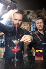 Handsome bartender serving cocktail to attractive woman in classy bar