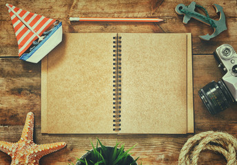 top view image of open blank notebook, wooden sailboat, nautical ripe and camera. travel and adventure concept. retro filtered image