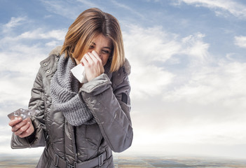 beautiful young woman sneezing and holding medicines