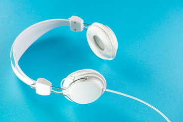 White headphones with cable isolated on blue background