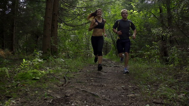 SLOW MOTION: A young couple jogging in the forest