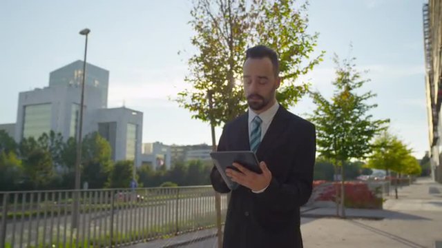 SLOW MOTION: Worried businessman checking news on digital tablet outdoors