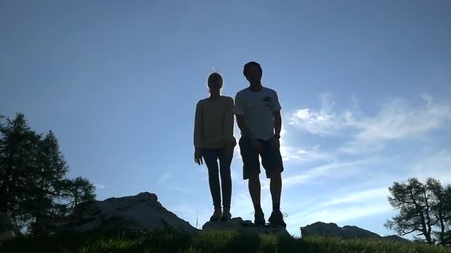 SLOW MOTION: Young couple jumping up on mountain peak