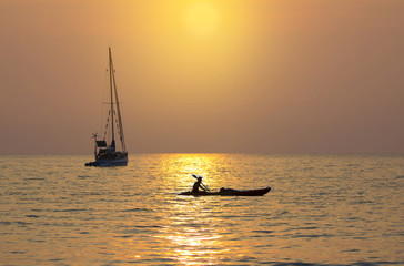 The kayak passed in front of the yatch during sunset