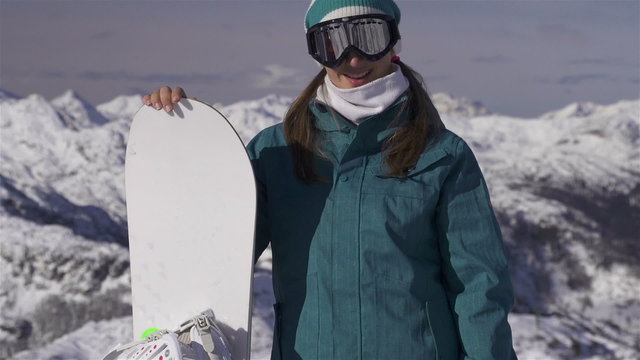 Portrait of snowboarder girl on the top of the mountain