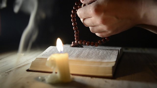 praying hands over a holy book