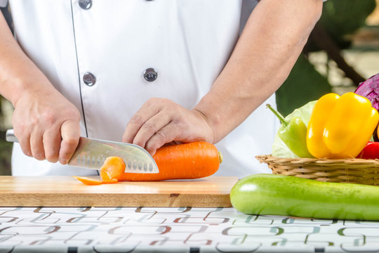 Chef cutting carrot on a wooden board