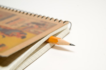 notebook and yellow pencil on over white