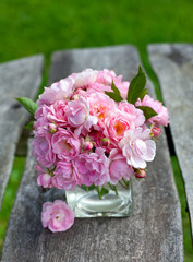 small pink garden roses on wooden surface
