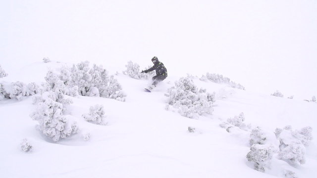 SLOW MOTION: Snowboarder riding powder in blizzard