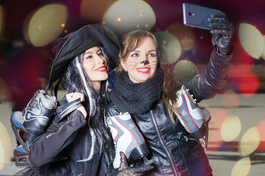 Two happy fancy dressed girls make selfie on mobile phone