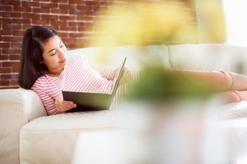 Smiling asian woman on couch reading