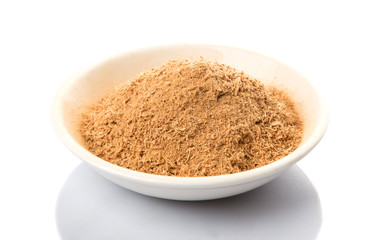 Dried galangal powder in white bowl over white background