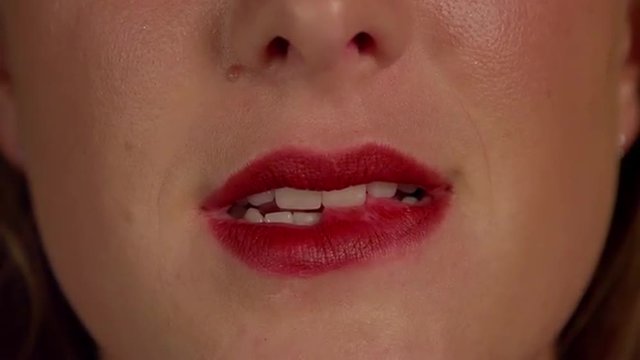 SLOW MOTION CLOSE UP: Woman biting her red lips