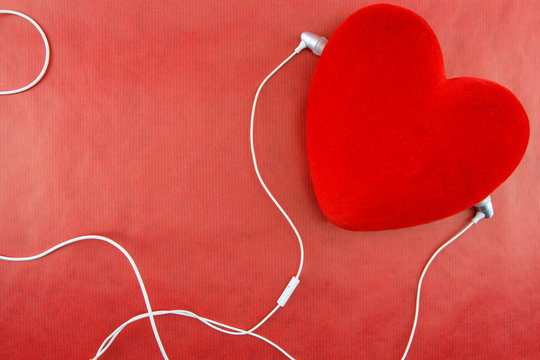 Heart with earphones closeup on red background